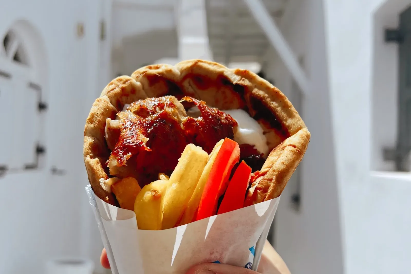 Pita Gyros mit Tzatziki in der Hand