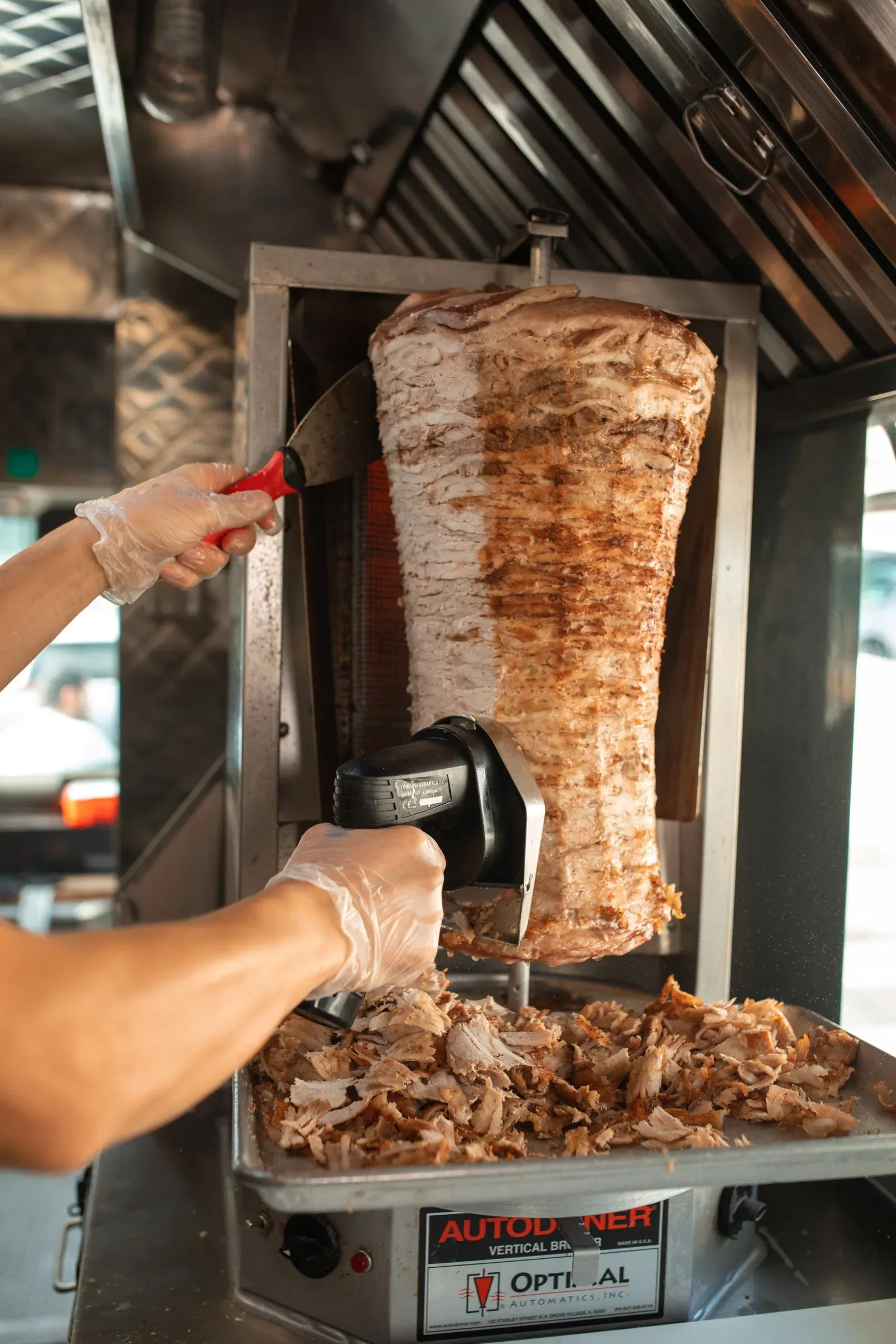 Hände schneiden Fleisch vom Gyros-Spieß